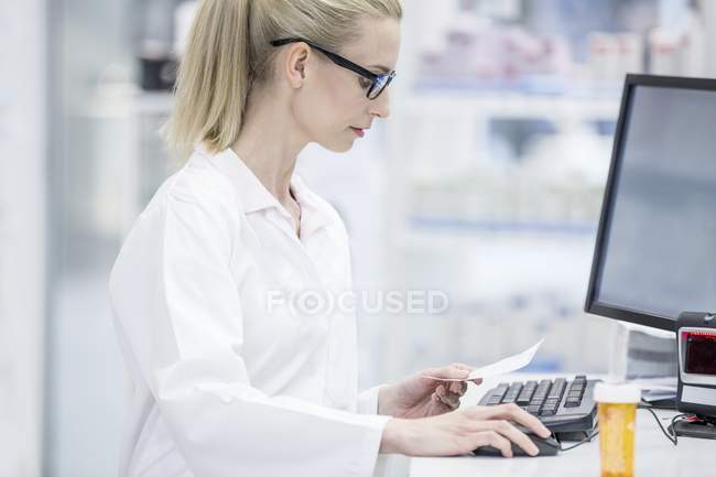 Farmacéutica femenina que trabaja en el ordenador en farmacia
. - foto de stock