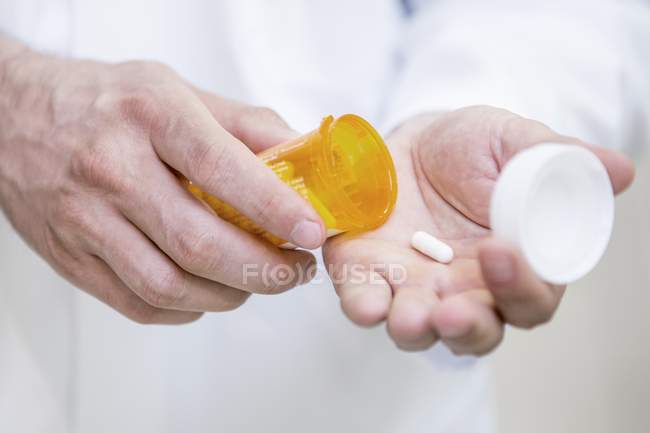 Крупный план аптекаря, наливающего таблетку в руки . — стоковое фото