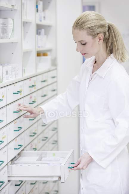 Pharmacie féminine à la recherche de médicaments dans le tiroir armoire en pharmacie . — Photo de stock
