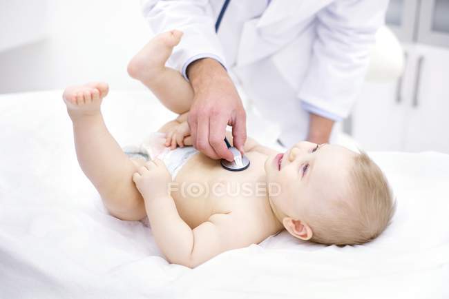 Doctor examining baby with stethoscope in medical clinic. — Stock Photo