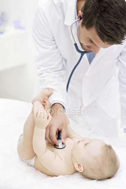 Doctor examining baby with stethoscope in medical clinic. — Stock Photo