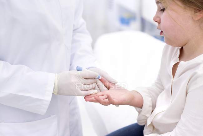 Petite fille ayant doigt test de piqûre dans la clinique médicale . — Photo de stock
