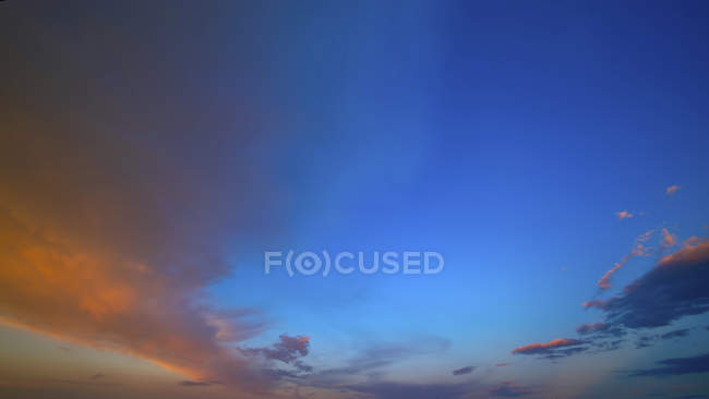 Хмари заходу сонця забарвлені жовтим сонячним світлом на блакитному небі . — стокове фото