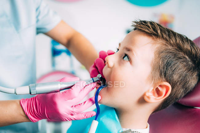 Manos de ortodoncista femenina trabajando con un niño pequeño . - foto de stock