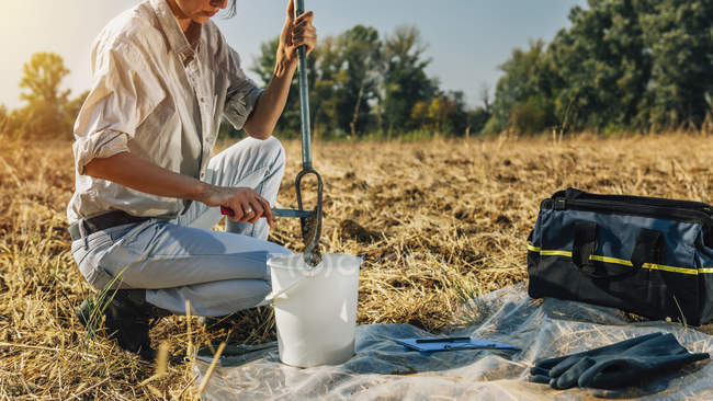 Feminino agrônomo colhendo amostra com sonda de solo amostrador . — Fotografia de Stock