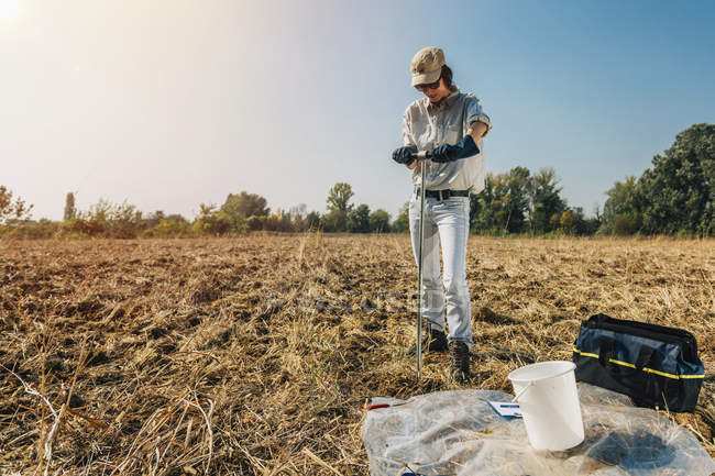 Agrónoma femenina tomando muestras con sonda de suelo . - foto de stock
