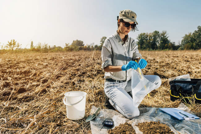 Agronomista abertura saco de amostra de solo no campo . — Fotografia de Stock