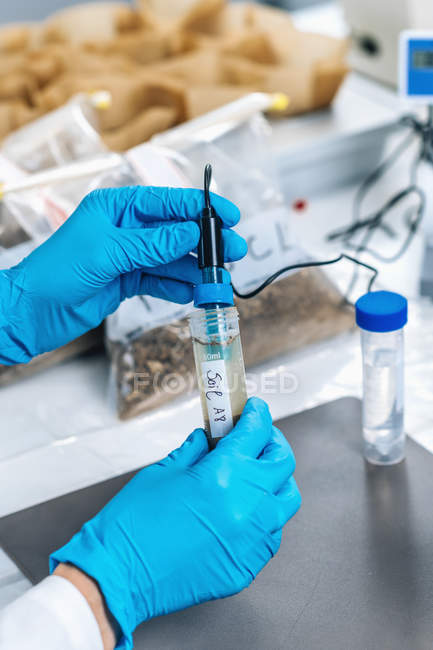 Mani dello scienziato in laboratorio che misura il pH dei campioni di terreno mediante pH metro elettronico . — Foto stock