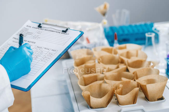 Close-up of female scientist taking notes in soil testing laboratory. — Stock Photo