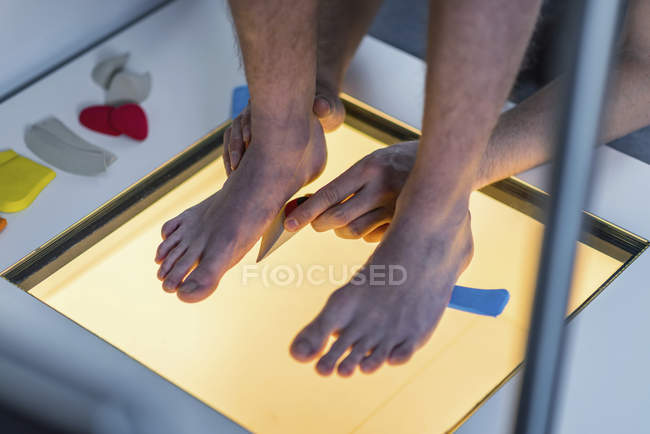 Physical therapist performing foot pressure scan for child on illuminated platform. — Stock Photo