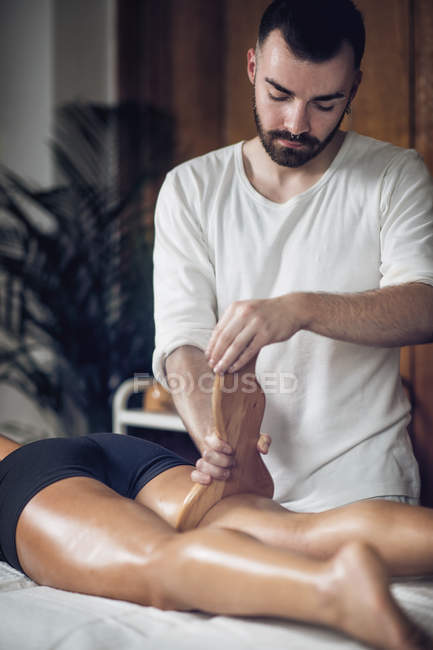 Cosmetologista masculino realizando na mulher anti-celulite maderoterapia . — Fotografia de Stock