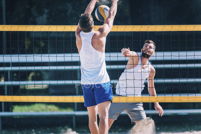 Jogadores de vôlei de praia bloqueando na net enquanto jogo . — Fotografia de Stock