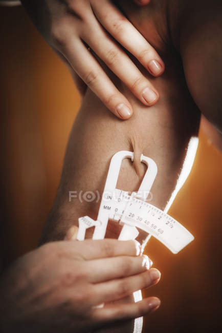 Médico midiendo grasa corporal en bíceps usando prueba de espesor del pliegue cutáneo en atleta masculino
. - foto de stock