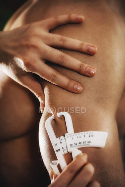 Physician measuring body fat on triceps using calipers test on male athlete. — Stock Photo