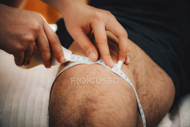 Médico midiendo la circunferencia del muslo con cinta métrica en atleta masculino . - foto de stock
