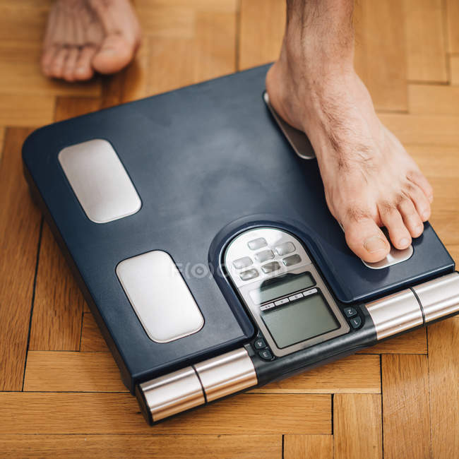 Feet of male athlete measuring body composition with floor scale. — Stock Photo