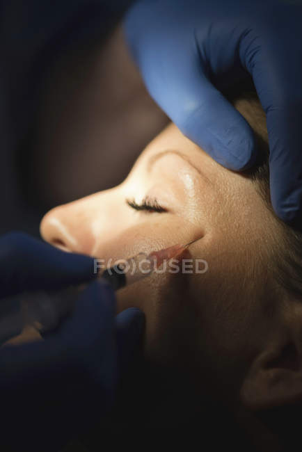 Крупный план женщины, получающей инъекцию ботокса в лицо в клинике . — стоковое фото