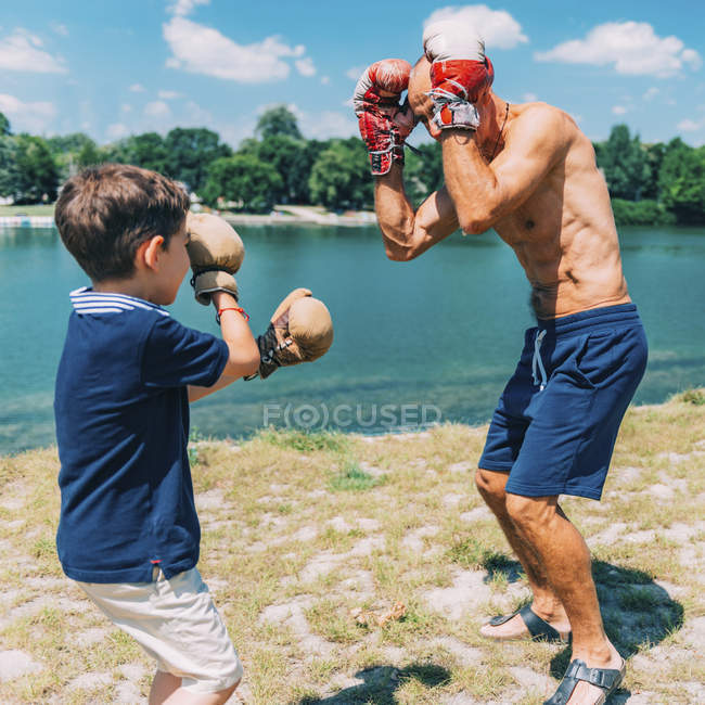 Großvater und Enkel boxen im Freien am See. — Stockfoto
