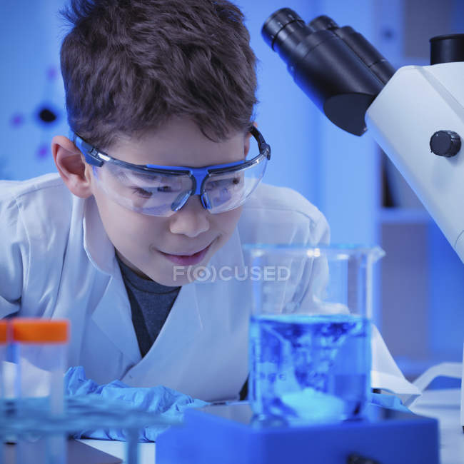Schoolboy using glassware and equipment in school laboratory. — Stock Photo