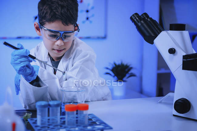 Colegial haciendo experimento científico en laboratorio de química escolar . - foto de stock