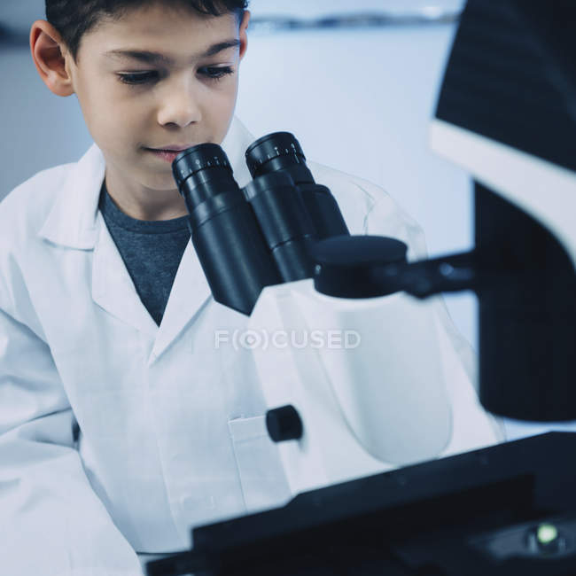 Schoolboy usando microscópio de luz no laboratório escolar . — Fotografia de Stock
