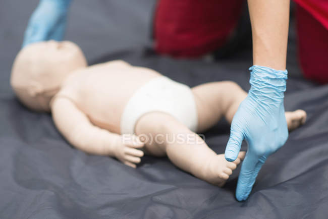 Manos del entrenamiento de RCP paramédico femenino en maniquí de bebé al aire libre . - foto de stock