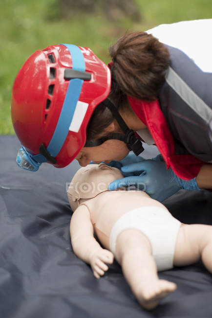 Female paramedic CPR training on baby dummy outdoors. — Stock Photo