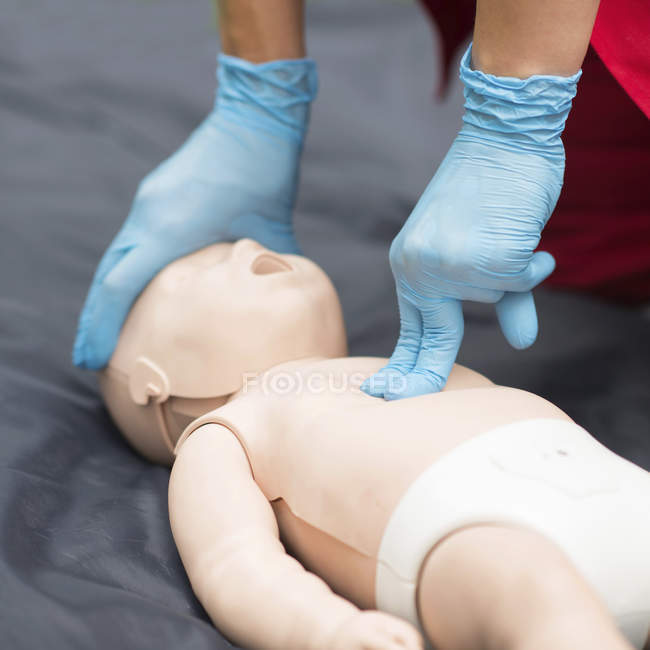 Hands of female paramedic CPR training on baby dummy outdoors. — Stock Photo
