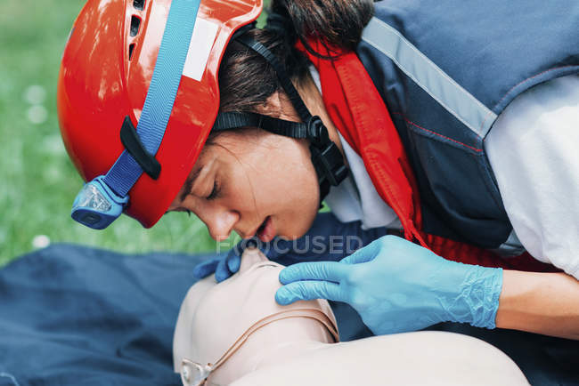 Paramédica femenina practicando boca a boca mientras entrena en RCP al aire libre . - foto de stock