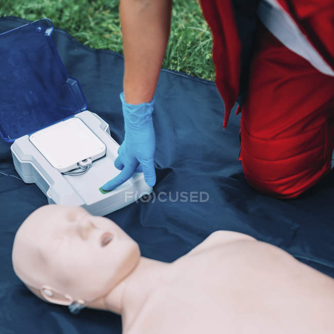 Female paramedic defibrillator training with dummy outdoors. — Stock Photo