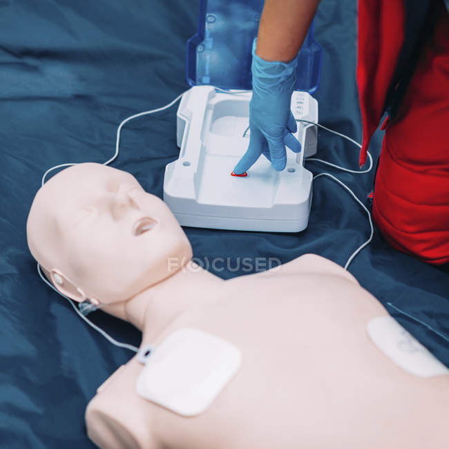 Рука женщины-парамедика с помощью дефибриллятора во время тренировок на открытом воздухе . — стоковое фото