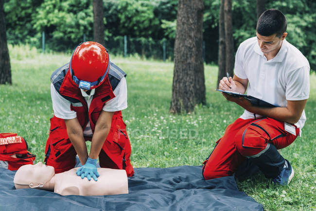 Woman with paramedic instructor CPR training on dummy outdoors. — Stock Photo
