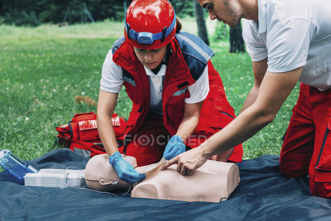 Hembra paramédica e instructora de entrenamiento de RCP en maniquí al aire libre . - foto de stock