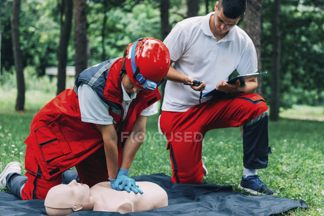 Woman with paramedic instructor CPR training on dummy outdoors. — Stock Photo