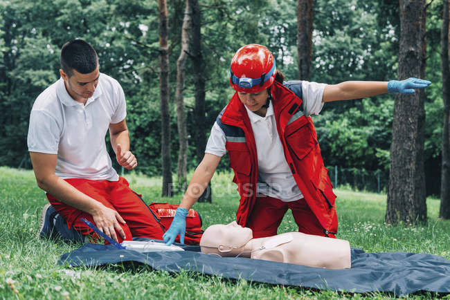 Feminino paramédico e instrutor de treinamento de RCP em dummy ao ar livre . — Fotografia de Stock