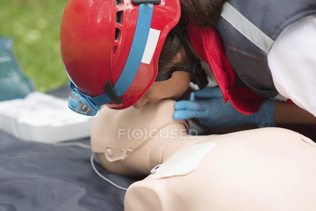 Женщина-парамедик практикует искусственное дыхание ртом в рот на открытом воздухе . — стоковое фото