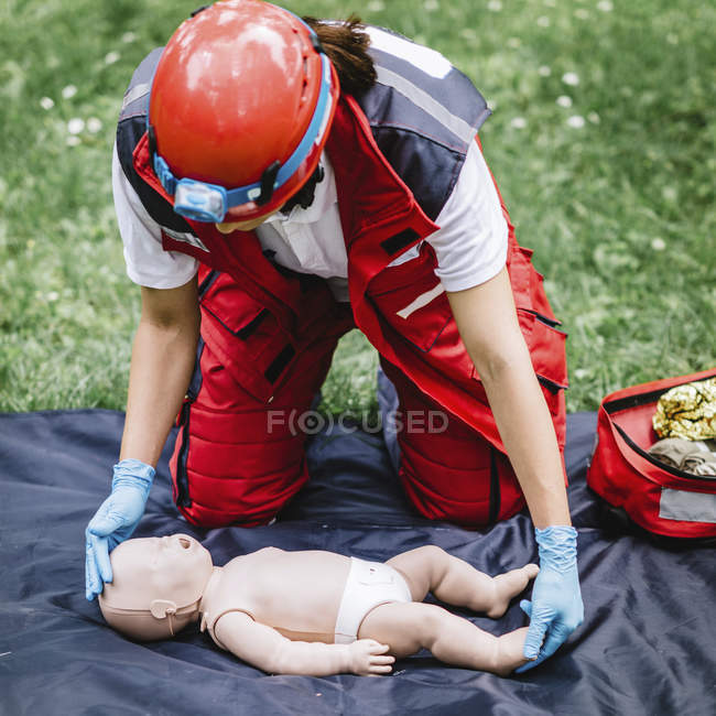Entrenamiento de RCP paramédico femenino en maniquí de bebé al aire libre . - foto de stock