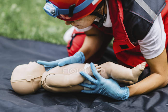 Entrenamiento de RCP paramédico femenino en maniquí de bebé al aire libre . - foto de stock