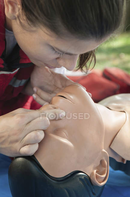Женщина-парамедик изо рта в рот практикуется на искусственном дыхании манекен . — стоковое фото