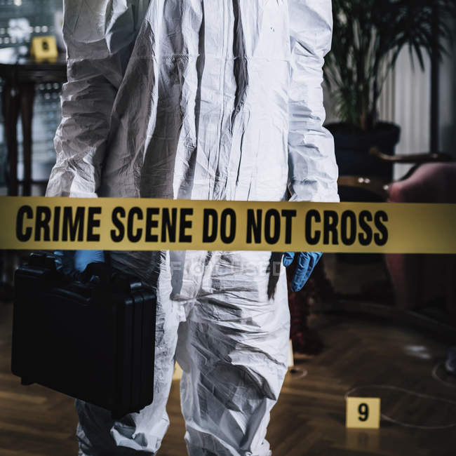 Forensics expert crossing cordon tape at crime scene. — Stock Photo