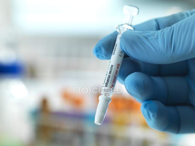 Primer plano del médico que sostiene la vacuna nasal antigripal preparada . - foto de stock