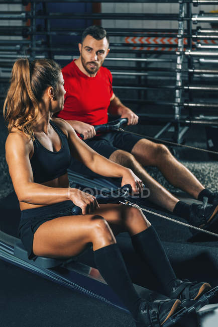 Fitte Frau und Mann beim Rudergerät-Workout im Fitnessstudio. — Stockfoto