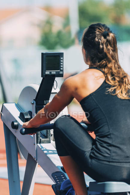 Mulher realizando o treino da máquina de remo no estádio
. — Fotografia de Stock