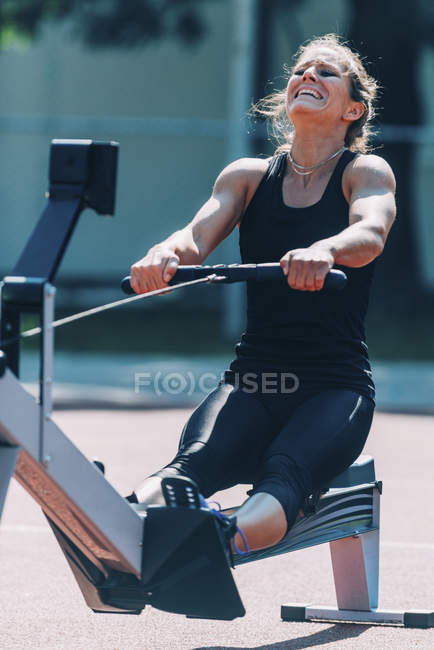Donna che esegue allenamento vogatore allo stadio . — Foto stock