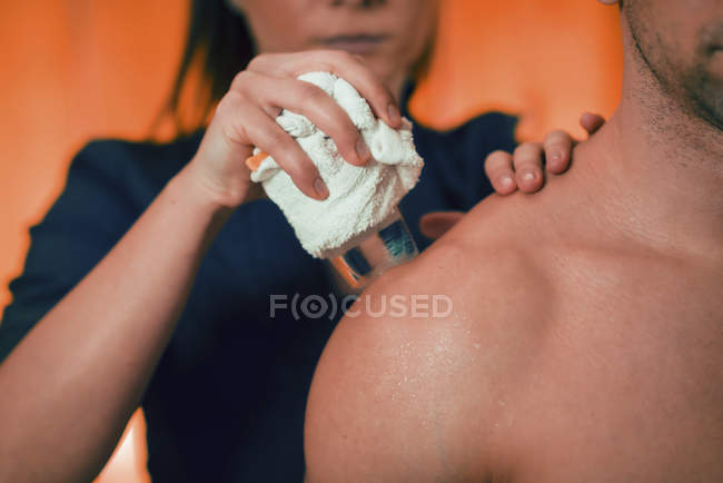 Physiothérapeute féminine effectuant un massage cryogénique pour la douleur aux épaules d'un athlète masculin . — Photo de stock