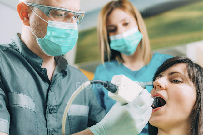 Dentists performing dental check-up for female patient. — Stock Photo