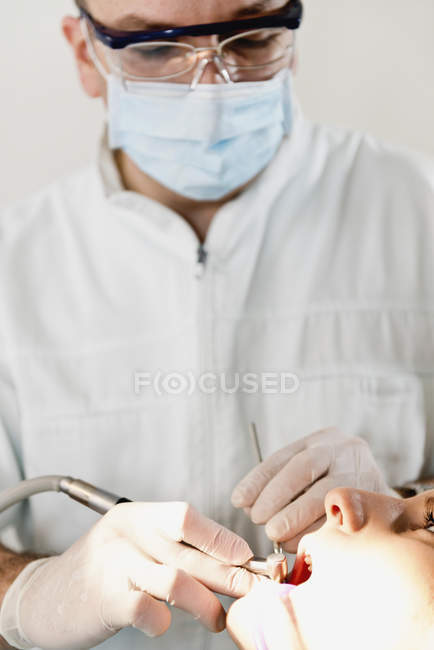 Médecin masculin effectuant un traitement dentaire pour le patient féminin . — Photo de stock