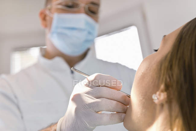 Male doctor performing dental check-up for female patient. — Stock Photo