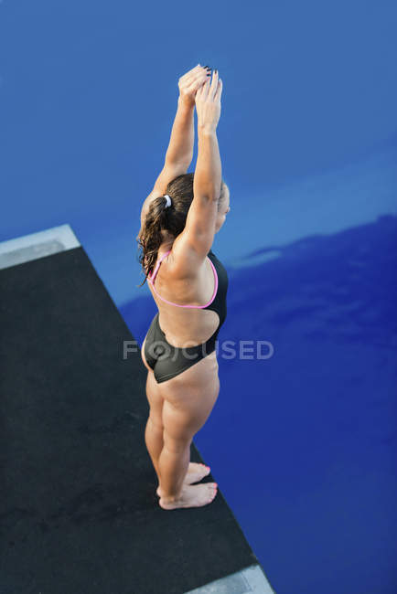 Высокоугол обзора женщины-ныряльщика с поднятыми руками на платформе . — стоковое фото