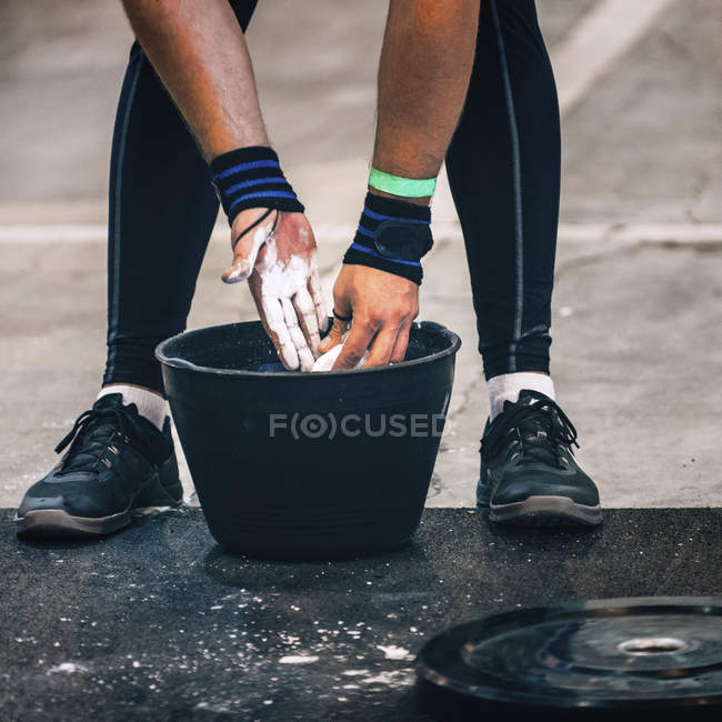Unterteil des männlichen Gewichthebers bereitet sich mit Kreidepuder im Eimer auf das Training vor. — Stockfoto